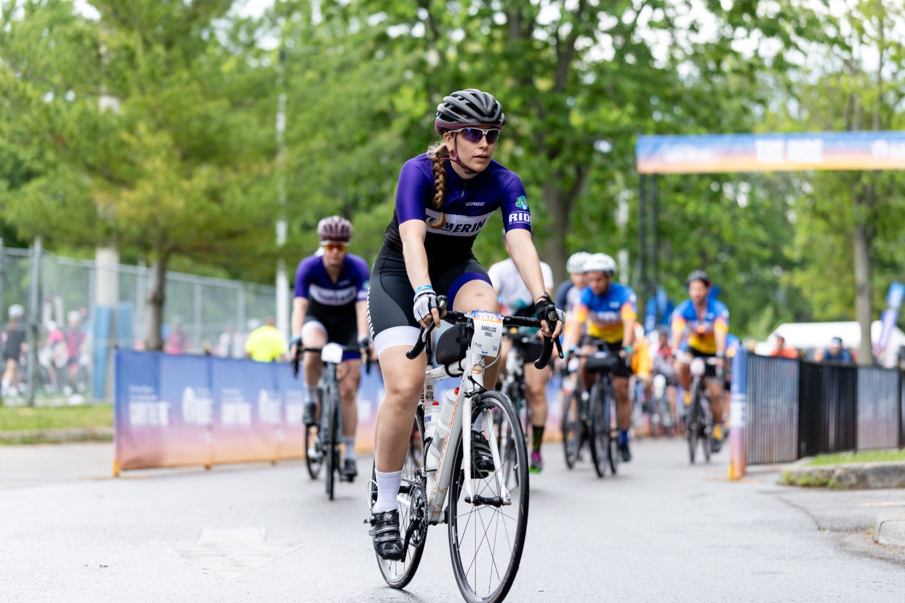 A rider in the 2026 Team Erin kit: purple top, white chest stripe, black shorts with purple and white cuffs