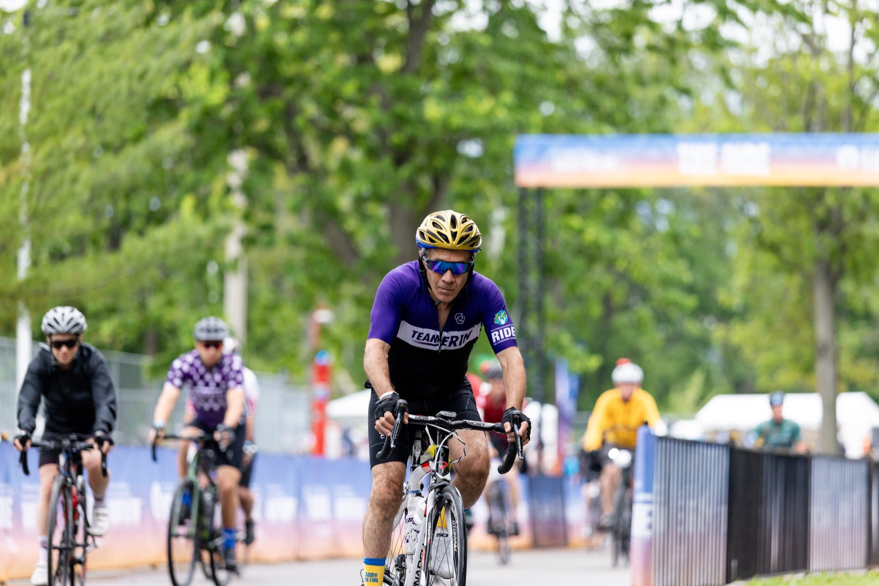 A Team Erin rider in purple on a white road bike